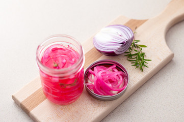 Obraz na płótnie Canvas Homemade pickled red onions. Pickling red onions is easy, simply marinate the onions in a brine with vinegar, salt and herbs. Pickled food can be preserved in glass jar for a very long time!