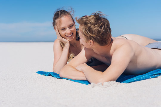 Young couple relaxing on a beach chatting