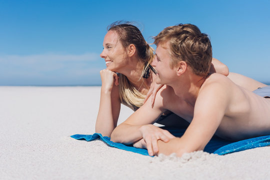 Happy young couple sunbathing on a sandy beach