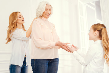 Obraz premium You are the prettiest granny. Tender nature daughter and thoughtful preteen granddaughter taking care of their beautiful grandmother and helping her with dressing up at home.