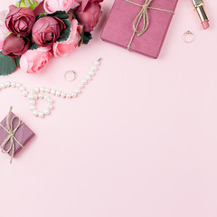 Beauty blog concept flat lay. Fashion accessories, flowers, cosmetics, jewelry on pink background, copyspace.