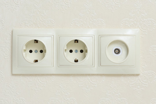 Two electrical outlets and a socket for a television antenna in a single beige case, made with one panel