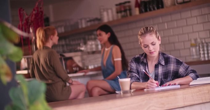 Young female hipster artist drawing sitting alone in urban cafe