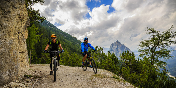 Mountain cycling couple with bikes on track, Cortina d'Ampezzo, Dolomites, Italy