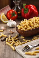 Italian raw pasta fusilli on the background of other ingredients for cooking