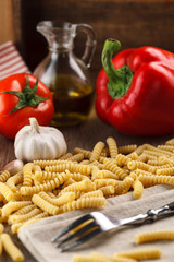 Italian raw pasta fusilli on the background of other ingredients for cooking