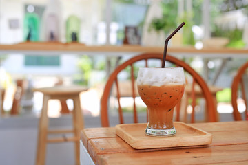 Iced coffee with milk on wooden table at cafe.