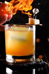 The bartender makes hot cocktail with fire and ice on the black background