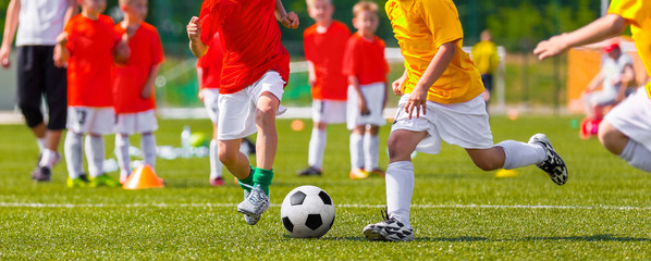 Obraz na płótnie Canvas Children football match. Boys Boys playing soccer match on professional football pitch. Football Stadium in the Background