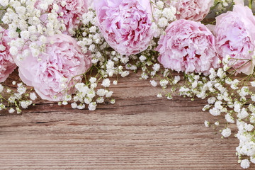 Pink peonies and gypsophila paniculata twigs on wood