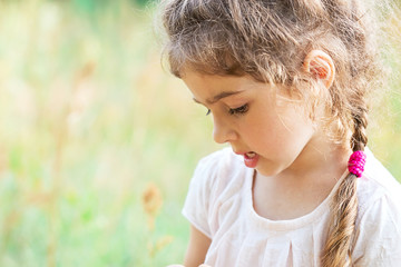 Cute Little girl is playing with on a meadow on a  sunny summer day.