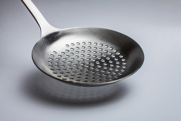 close-up of a slotted spoon on a white background