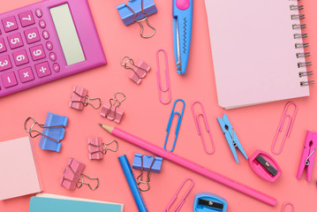 Stationary concept, Flat Lay top view Photo of Scissors, pencils, paper clips,calculator,sticky note,stapler and notepad in pink and blue tone on pink background with copy space
