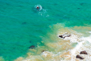 Aerial view over green turquoise water waves in Byron Bay, Australia. Nature background with ocean waters and rocks in sunny day.