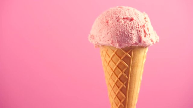 Ice cream. Strawberry or raspberry flavor icecream in waffle cone rotated over pink background. Sweet dessert closeup. 4K UHD video footage. 3840X2160