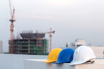 Group of safety helmet and the blueprint at construction site with crane background