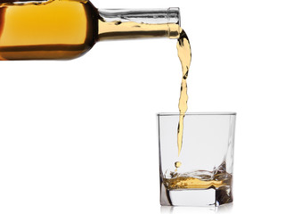 whiskey or cognac poured into a glass from a bottle isolated on a white background