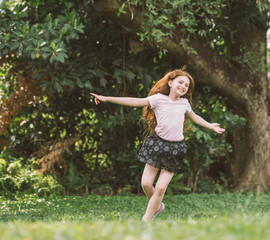 Naklejka na ściany i meble young girl with arms open enjoying her freedom at the park so happy relax dance