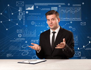 Young handsome businessman sitting at a desk with blue charts and data behind him