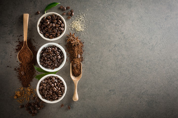 Different varieties of coffee beans with sugar and green leaf on dark vintage background. From top view