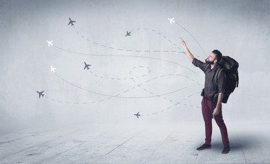 Handsome young man standing with a backpack on his back and little planes in the background