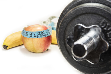 Fototapeta premium Dumbbell and an apple with a tape measure, isolated on white