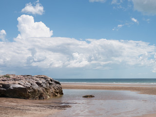 blue cloudy sky over tropical beach, creek in foreground