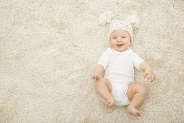Happy Baby in Hat and Diaper Lying on Carpet Background, Smiling Infant Kid Boy in White Clothing,...