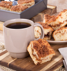 Piece of cinnamon swirl crumb cake next to a cup of coffee