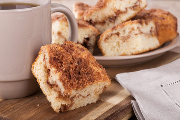 Closeup of a piece of cinnamon swirl crumb cake leaning on a cup of coffee
