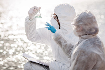 Scientist or biologist wearing protective uniforms examining the liquid contents of a test tube....