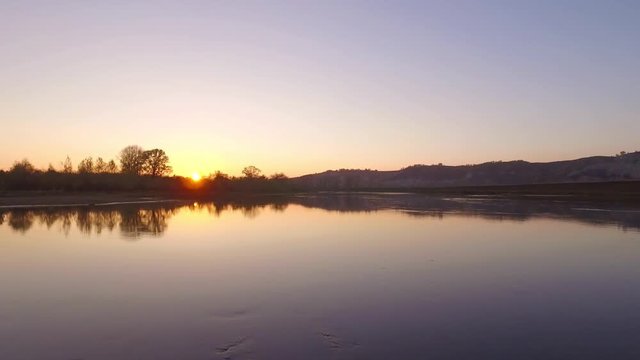 Overgrown broad river sunset sky reflection on water - aerial view