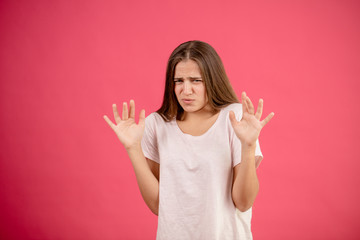 young Caucasian female in casual oufit is fastidious on the isolated pink background. disdain