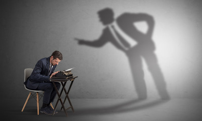 Little man working and a big shadow arguing with him
