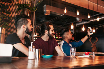 Group of arabian friends taking selfie in lounge bar. Mixed race young men having fun together