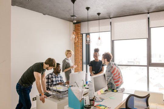 five young people are standing in the office and making plan of working in the loft room