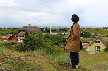 The girl looks at the sea and typical scandinavian house. Island Fanoe, Denmark.