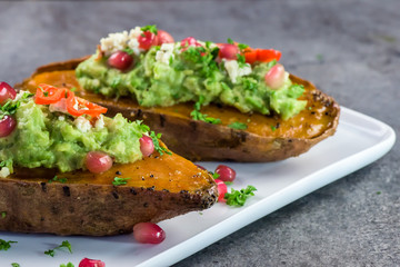 Baked sweet potatoes with guacamole, feta cheese and pomegranate - bataty - closeup