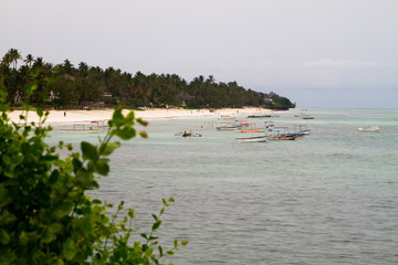 ZANZIBAR, TANZANIA - JANUARY 05: Blue Indian Ocean landscape with boats and people on the beach, seen from inside The Rock restaurant in Zanzibar, Tanzania on January 6th, 2018