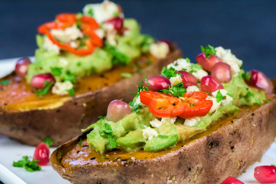 Baked sweet potatoes with guacamole, feta cheese and pomegranate - bataty - closeup