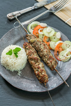 Minted lamb kebabs on skewers with rice and cucumber and tomato salad