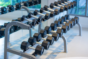Rows of metal heavy dumbbells on rack in the gym for athletic and Healthy concept / sport club. Weight Training Equipment. Close up many dumbbell in sport fitness center