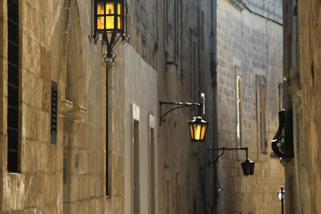 wąska uliczka starego miasta w europie południowej z latarniami i domami z kamienia