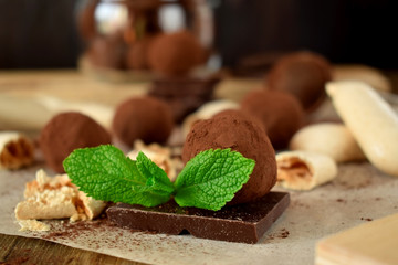 Chocolate truffles sprinkled with cocoa powder and leaves of mint
