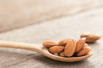 Almonds in the wooden spoon on the table.