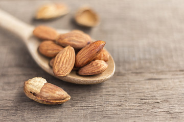 Almonds in the wooden spoon on the table.
