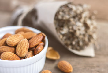 Almonds in a white ceramic bowl on the wooden table.