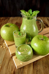 Green smoothie in glass vessels on wooden background
