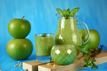 Green smoothie in glass vessels on blue background