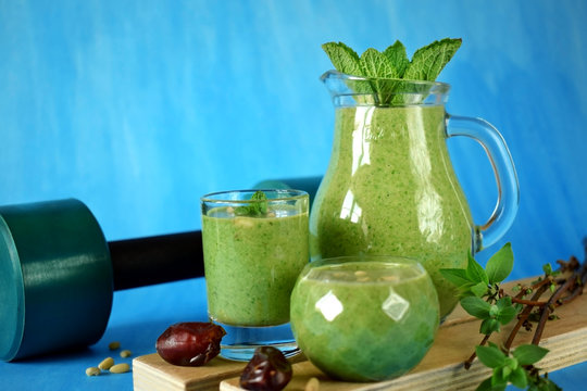 Green smoothie in glass vessels on blue background